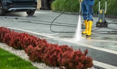 An expert cleaning driveway with pressure washer.